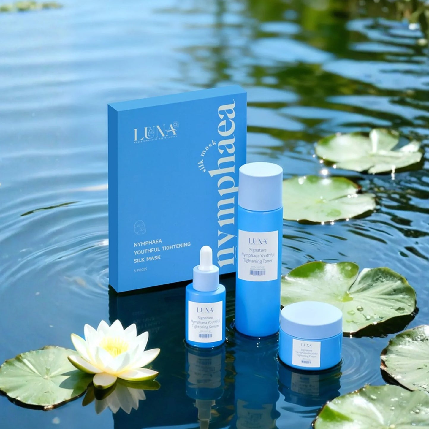 Nymphaea Youthful Tightening skincare set with blue packaging on water with lily pads and a white lotus flower.